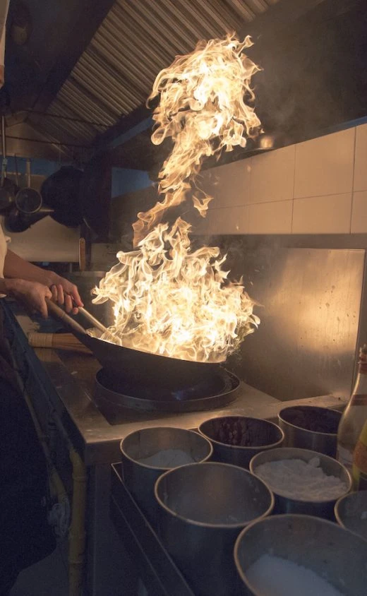 Chef cooking with flambé wok